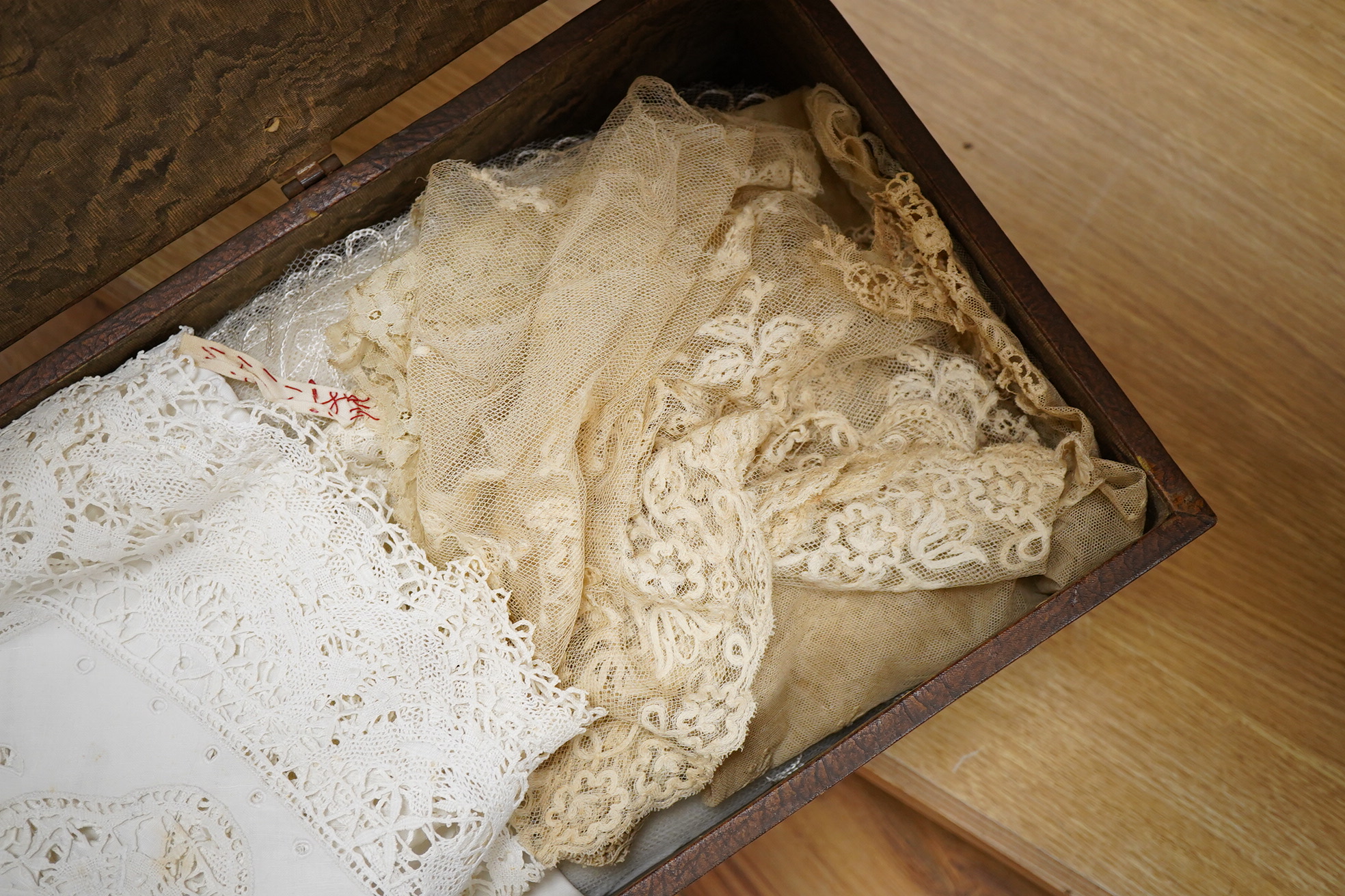 A small box/trunk containing mixed crochet, embroidered anglaise and drawn thread table linens, christening gown, damask cloths and various pieces of lace etc.Ornate circular cloth 112cm diameter. Condition - most need r
